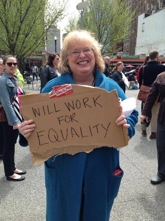 Peggy holding a sign that says will work for equality