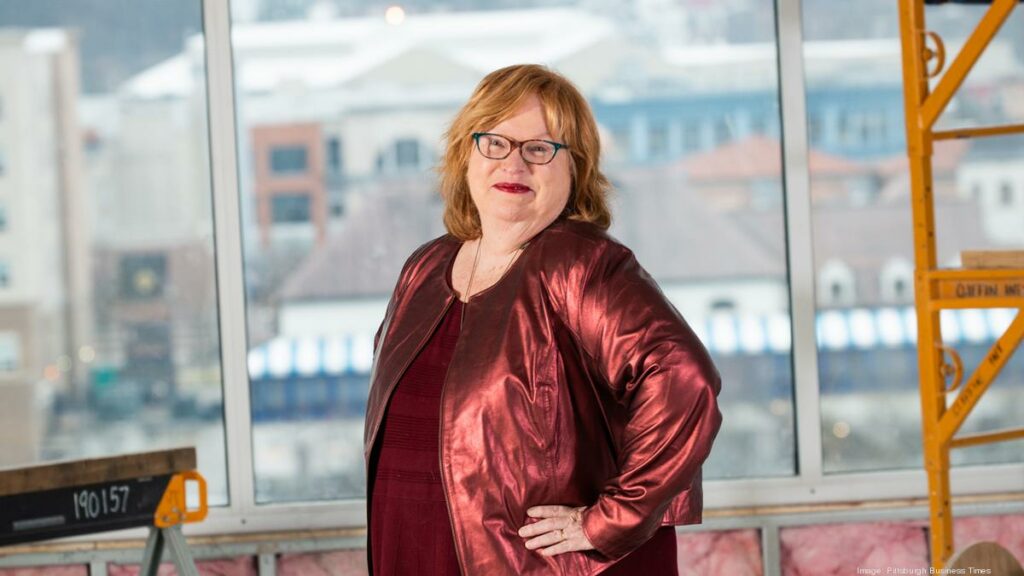 Peggy in a red dress standing in front of a bank of windows